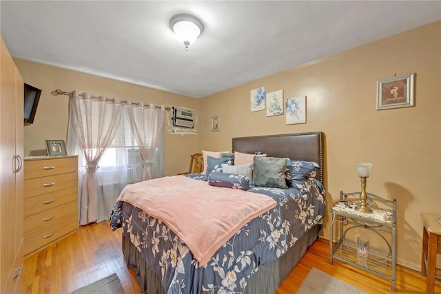 bedroom with hardwood / wood-style flooring and a wall unit AC