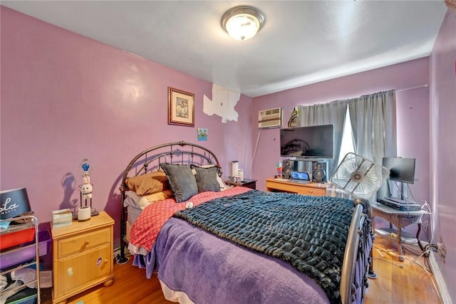 bedroom featuring a wall mounted AC and light hardwood / wood-style floors