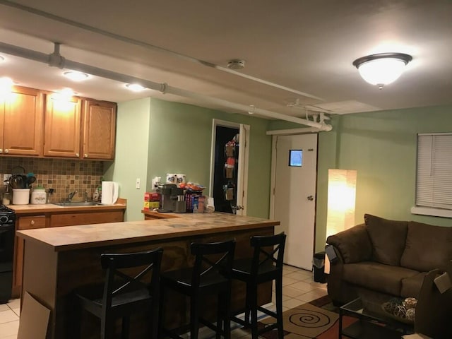 kitchen with sink, wood counters, tasteful backsplash, a breakfast bar area, and a kitchen island