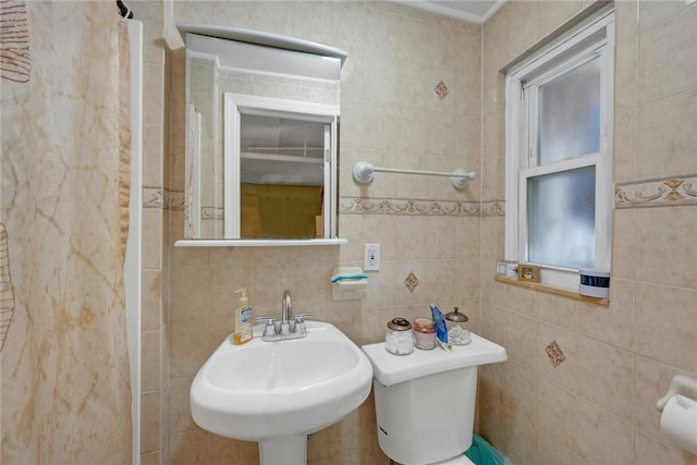 bathroom featuring toilet, tile walls, and sink