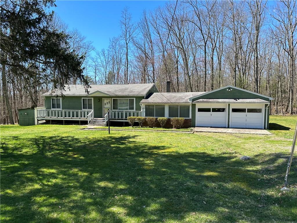 ranch-style house featuring a front lawn, covered porch, and a garage