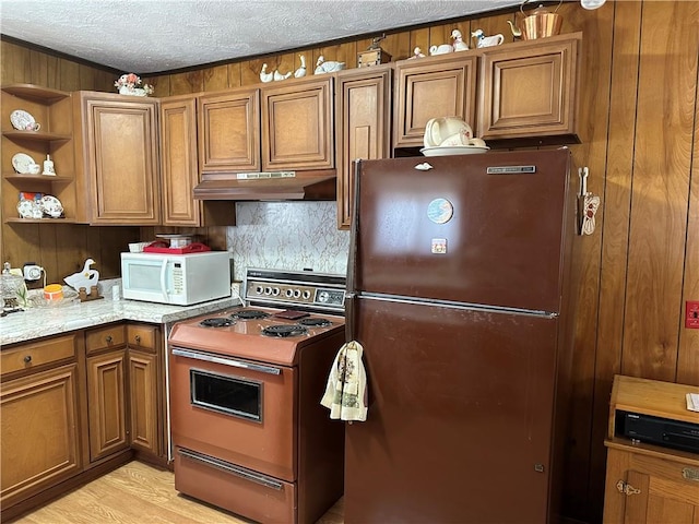 kitchen featuring a textured ceiling, range, light hardwood / wood-style floors, fridge, and wood walls