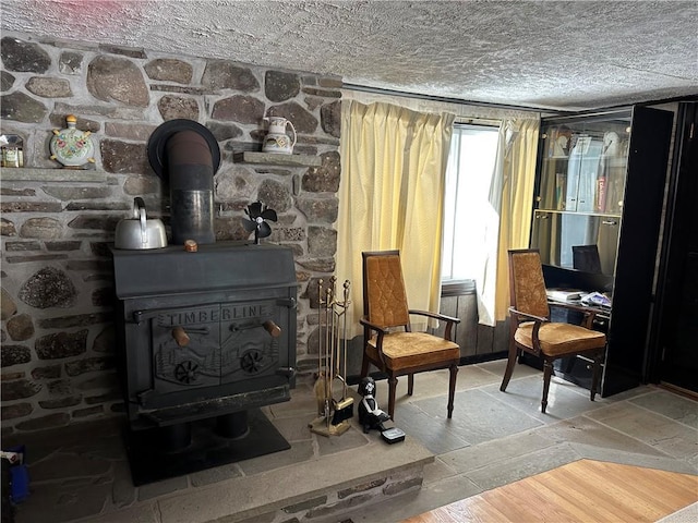 living area featuring wood-type flooring, a textured ceiling, and a wood stove