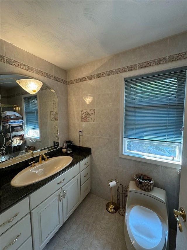 bathroom with tile patterned floors, plenty of natural light, tile walls, and vanity