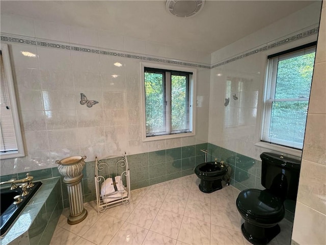 bathroom featuring a tub, a bidet, tile walls, and toilet