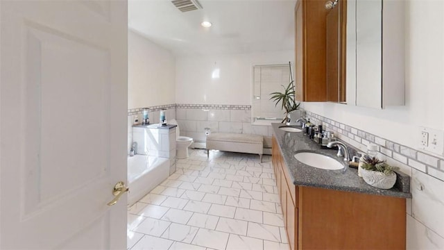 bathroom featuring vanity, tile patterned floors, a bathing tub, toilet, and tile walls