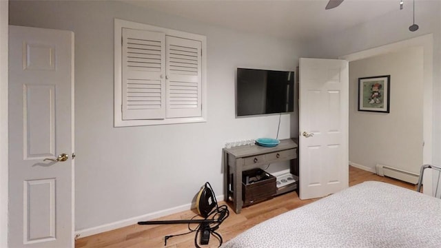 bedroom with ceiling fan, a baseboard radiator, and wood-type flooring