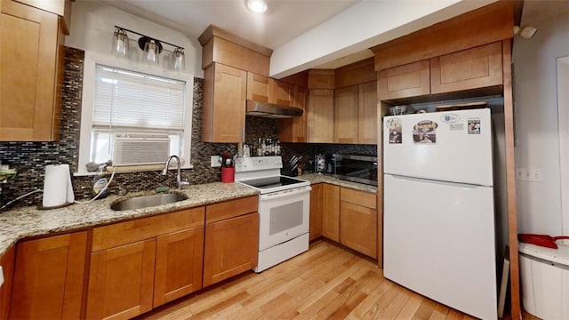 kitchen with light wood-type flooring, decorative backsplash, white appliances, and sink