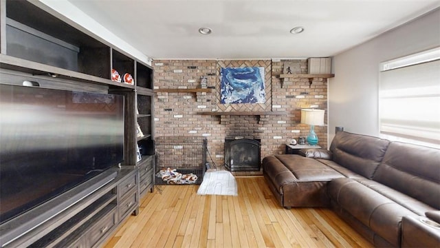 living room featuring a brick fireplace, light hardwood / wood-style flooring, and brick wall