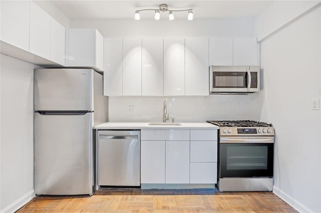 kitchen featuring decorative backsplash, stainless steel appliances, light parquet floors, sink, and white cabinetry