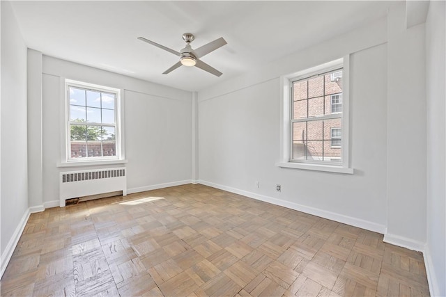 empty room with light parquet floors, radiator, and ceiling fan