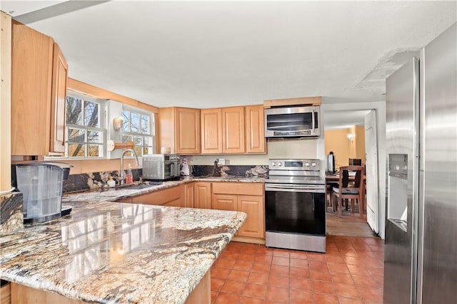 kitchen with light stone countertops, light brown cabinets, stainless steel appliances, and sink