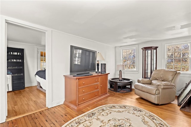 living room featuring a healthy amount of sunlight, wood-type flooring, and crown molding