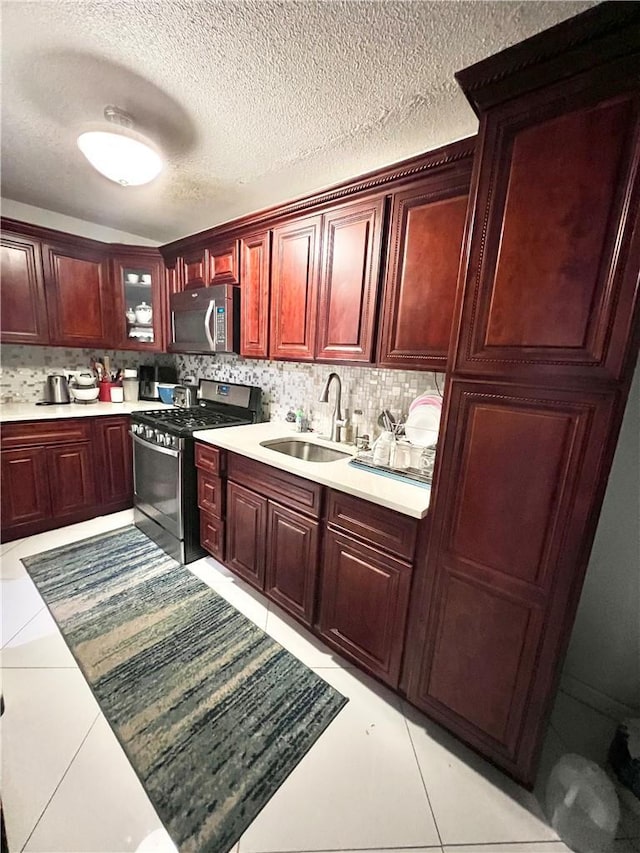 kitchen featuring decorative backsplash, light tile patterned flooring, sink, and appliances with stainless steel finishes