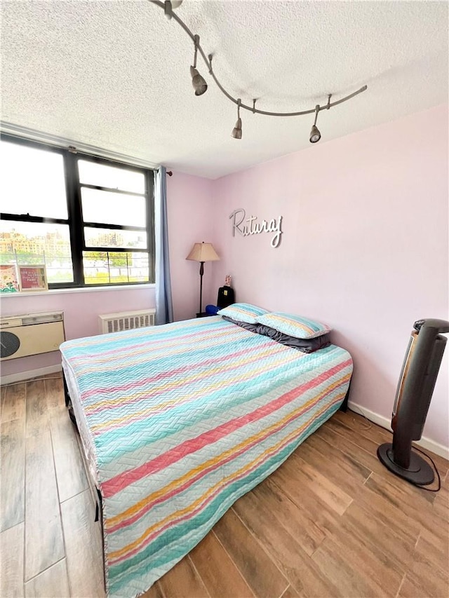 bedroom with hardwood / wood-style flooring, a textured ceiling, and radiator