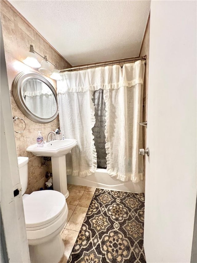 bathroom featuring tile patterned flooring, toilet, a textured ceiling, and shower / tub combo with curtain