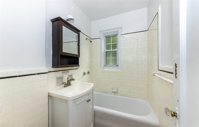 bathroom featuring tiled shower / bath, vanity, and tile walls