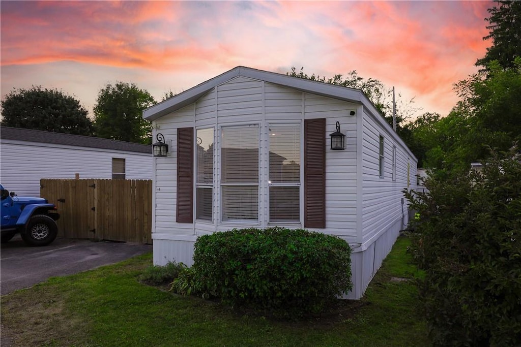 property exterior at dusk featuring a yard