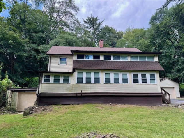 back of house featuring a yard, an outbuilding, and a garage