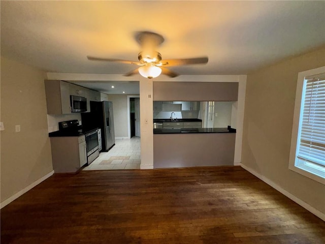 kitchen featuring kitchen peninsula, light wood-type flooring, stainless steel appliances, ceiling fan, and sink