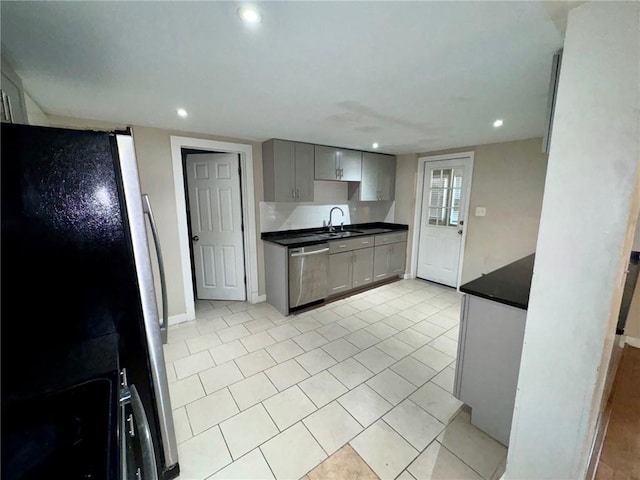 kitchen with appliances with stainless steel finishes, gray cabinets, light tile patterned floors, and sink