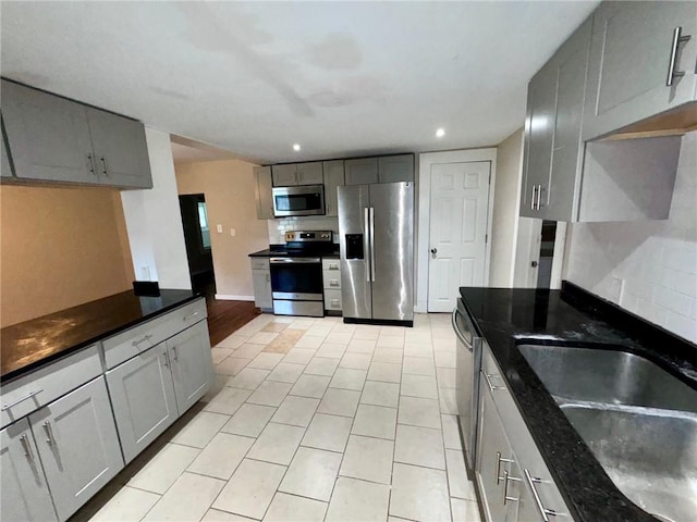 kitchen featuring light tile patterned flooring, stainless steel appliances, gray cabinets, and sink