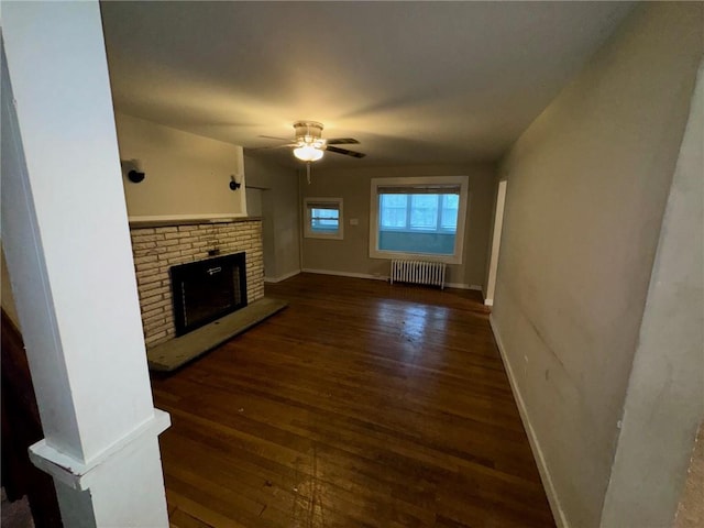 living room with a fireplace, ceiling fan, radiator heating unit, and dark wood-type flooring