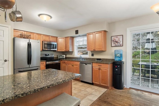 kitchen featuring dark stone counters, plenty of natural light, stainless steel appliances, and sink