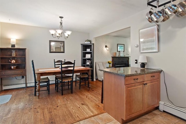 kitchen featuring a chandelier, light hardwood / wood-style floors, baseboard heating, and dark stone countertops