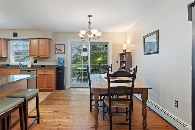 dining area featuring baseboard heating, sink, light hardwood / wood-style flooring, and an inviting chandelier