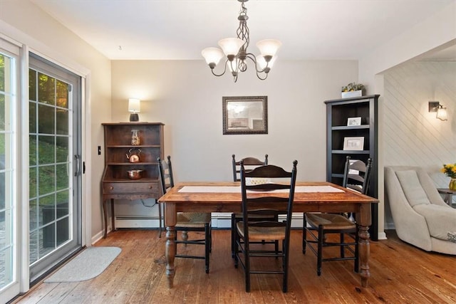 dining room featuring hardwood / wood-style flooring, a baseboard heating unit, and an inviting chandelier