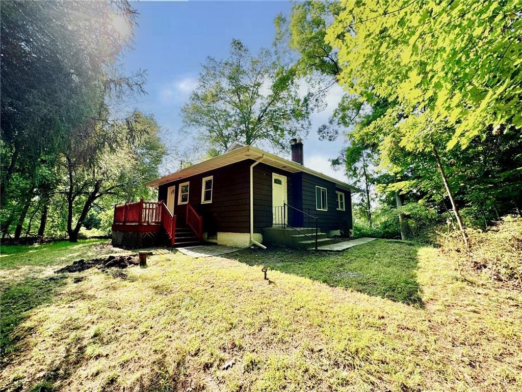 view of property exterior featuring a wooden deck and a lawn