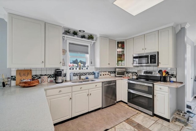 kitchen with decorative backsplash, stainless steel appliances, white cabinetry, and sink