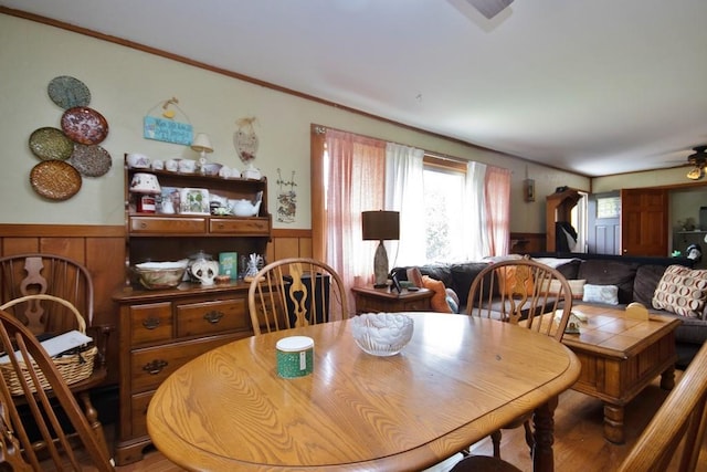 dining area with ceiling fan, ornamental molding, and wooden walls