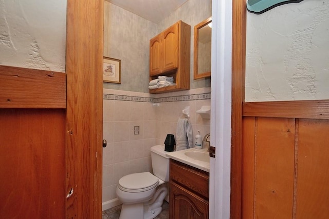 bathroom with vanity, tile walls, and toilet