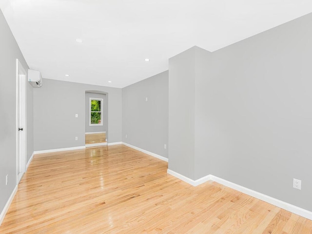 unfurnished room featuring a wall unit AC and light hardwood / wood-style floors