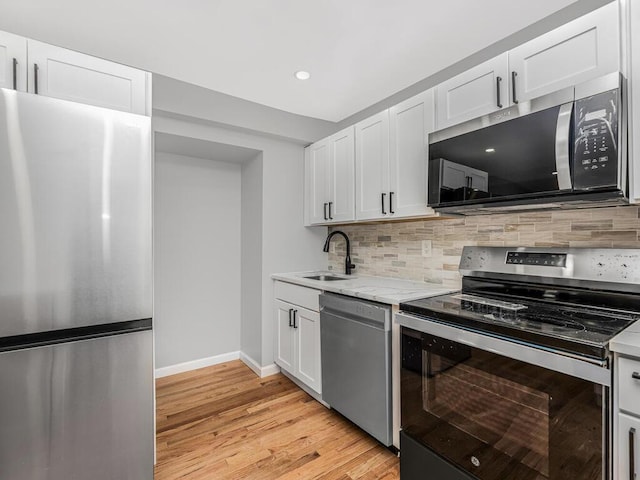 kitchen featuring sink, white cabinets, stainless steel appliances, and light hardwood / wood-style flooring