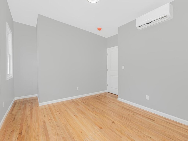 empty room featuring an AC wall unit and light hardwood / wood-style flooring