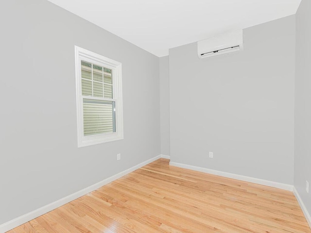 unfurnished room featuring hardwood / wood-style floors and an AC wall unit