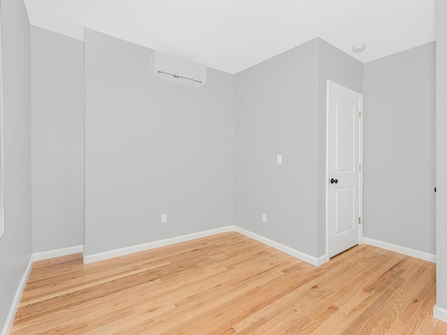 unfurnished room featuring hardwood / wood-style floors and an AC wall unit