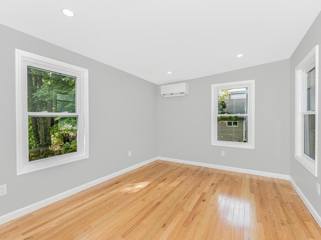 spare room featuring light wood-type flooring and a wall unit AC