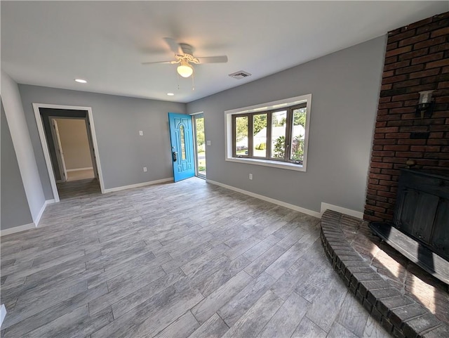 unfurnished living room featuring ceiling fan, light hardwood / wood-style flooring, and a brick fireplace