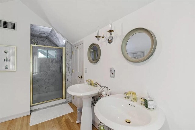 18 Brushy Neck Ln, Westhampton, NY 11977 - bathroom with a marble finish shower, vaulted ceiling, wood finished floors, and two sinks