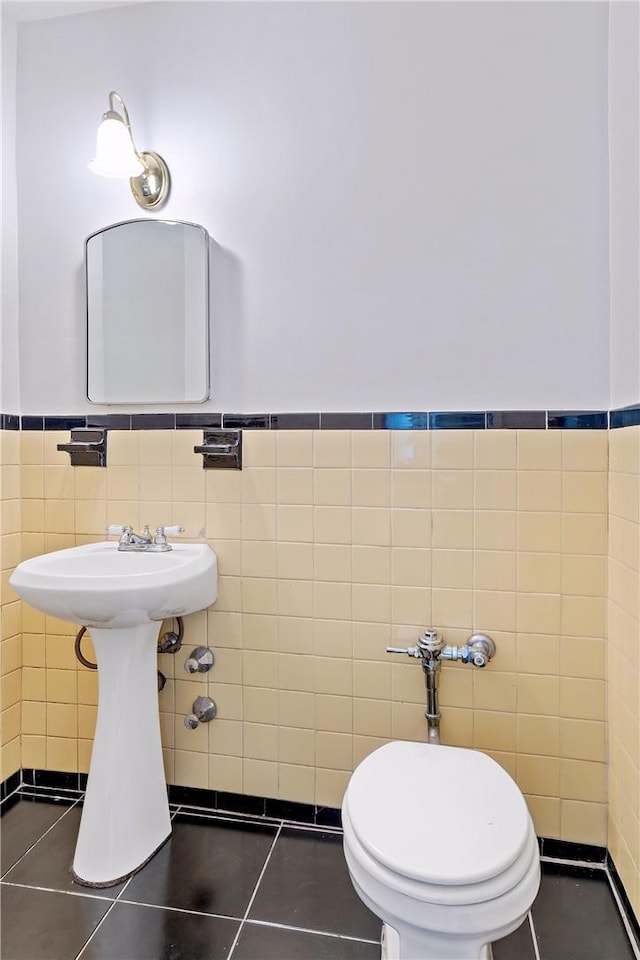 bathroom featuring tile patterned floors, toilet, and tile walls