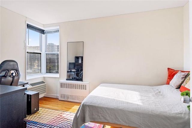 bedroom with radiator heating unit and hardwood / wood-style flooring