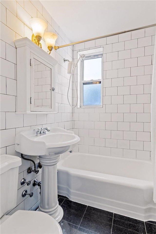 bathroom featuring tile patterned floors, toilet, tile walls, and tiled shower / bath