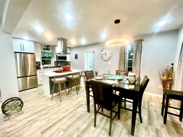 dining room featuring sink, light hardwood / wood-style flooring, and an inviting chandelier