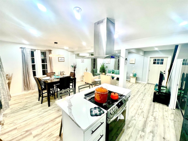 kitchen with hanging light fixtures, light hardwood / wood-style flooring, island exhaust hood, stainless steel electric range, and white cabinets