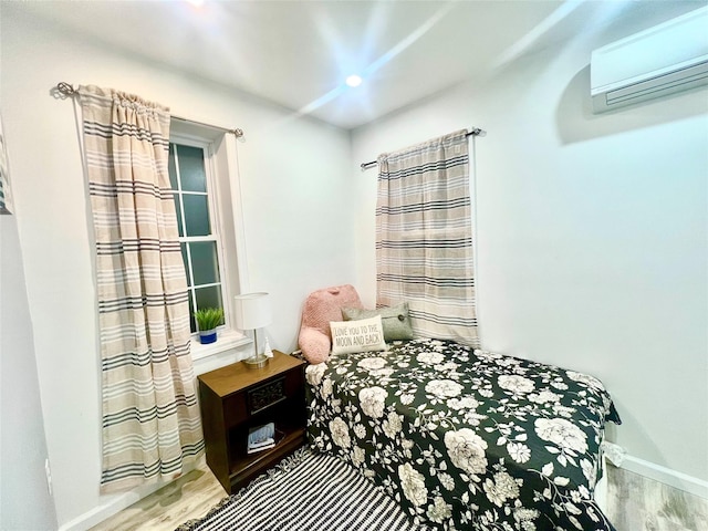 bedroom with light hardwood / wood-style floors and an AC wall unit