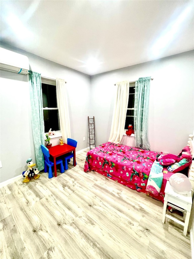 bedroom with a wall mounted air conditioner and hardwood / wood-style flooring